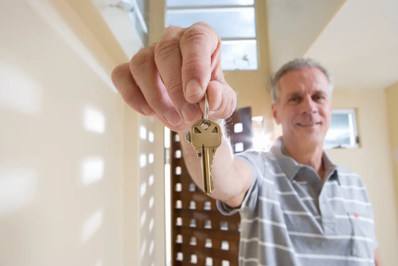 Mann hält einen Wohnungsschlüssel in die Kamera